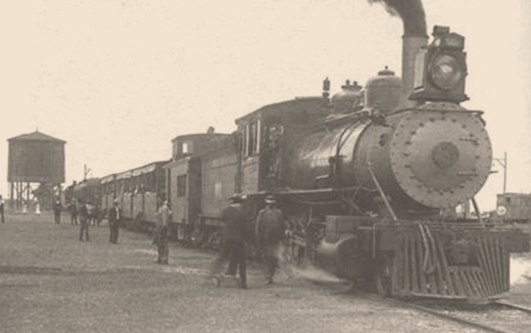 A train pulling into a station in the late 1800s